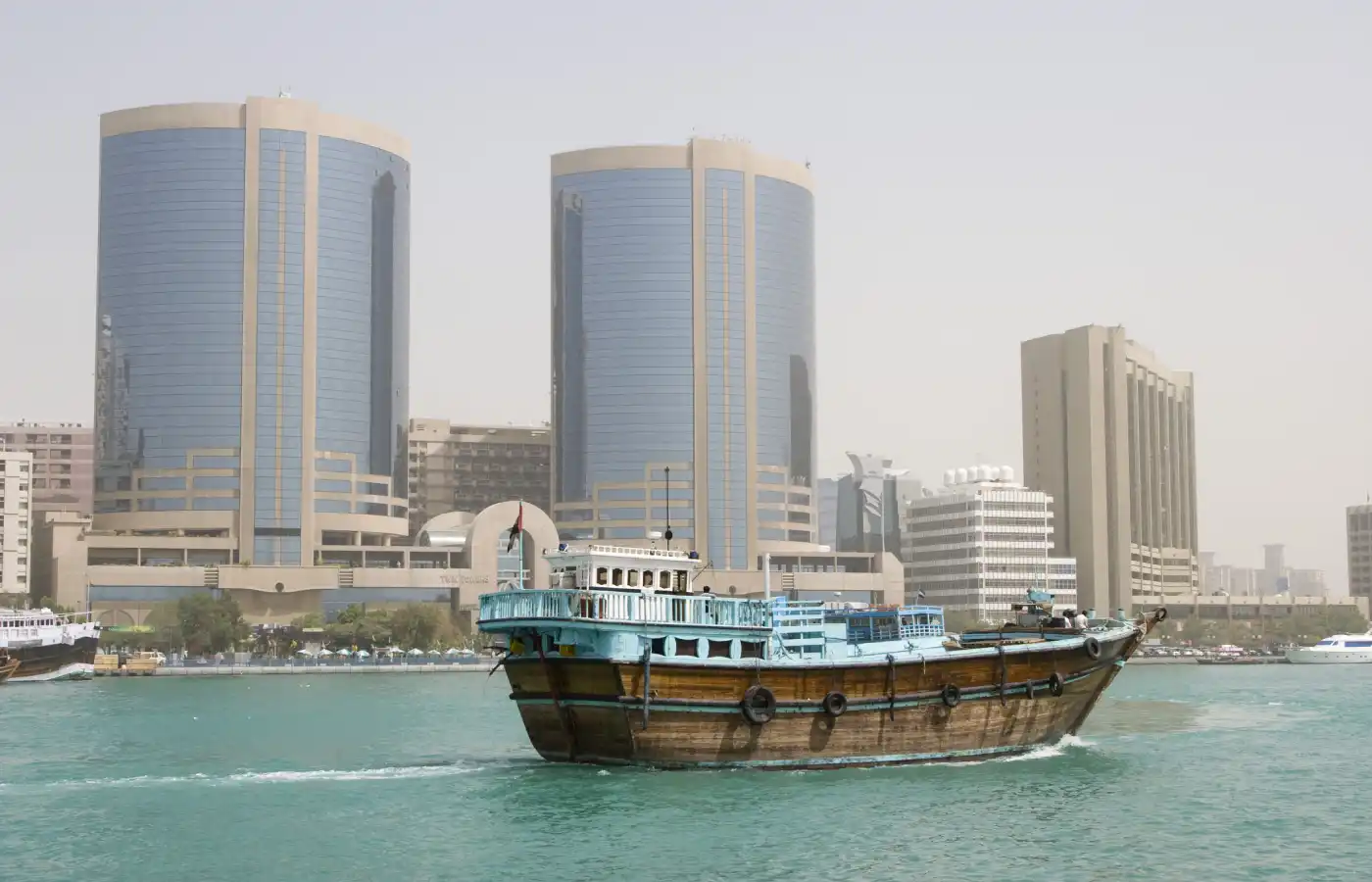 A dhow old wooden sailing vessel cruises down Dubai Creek.