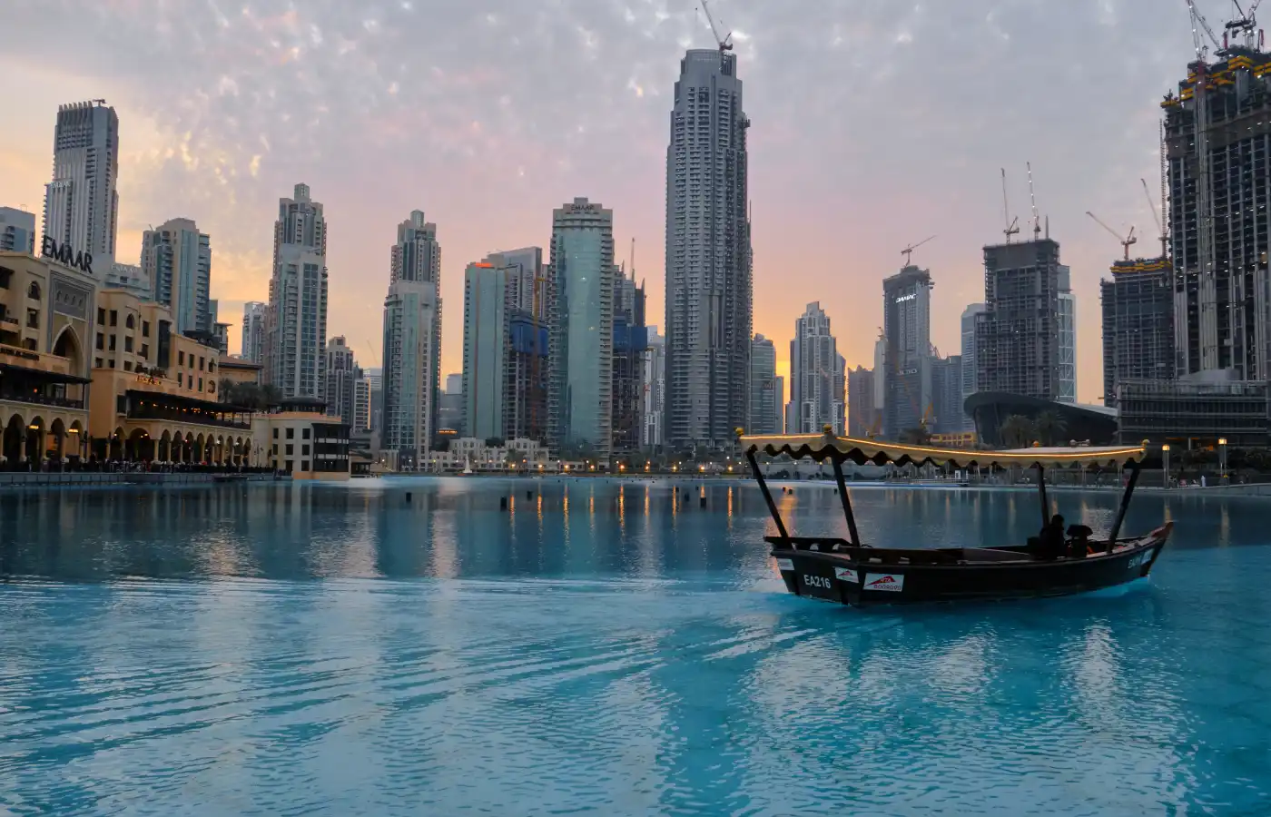 Abra (wooden boat) sailing next to tallest building in the world Burj Khalifa in Dubai.