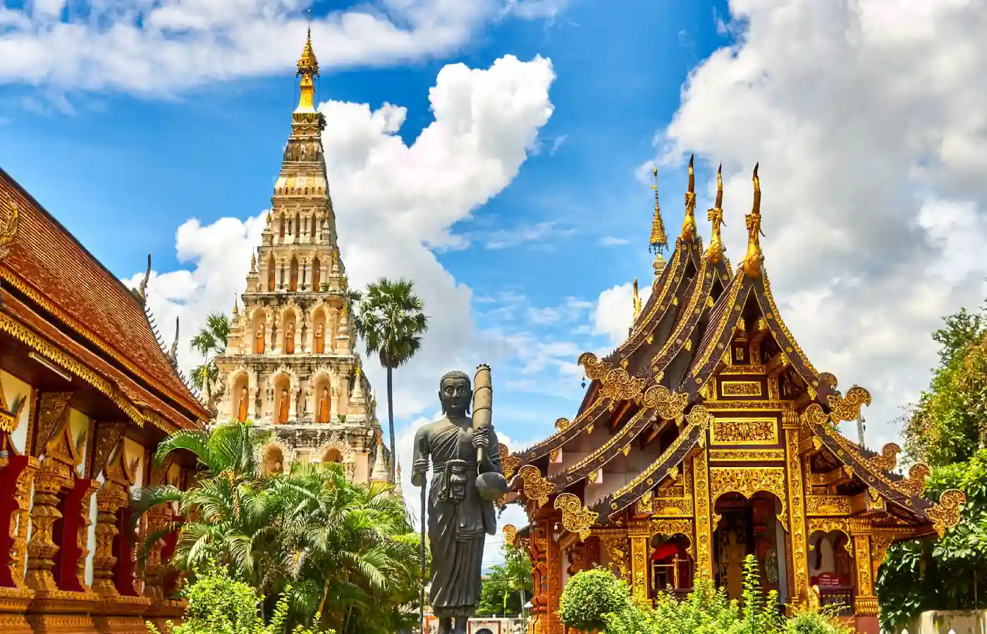Standing statue and temples in Thailand during daytime.