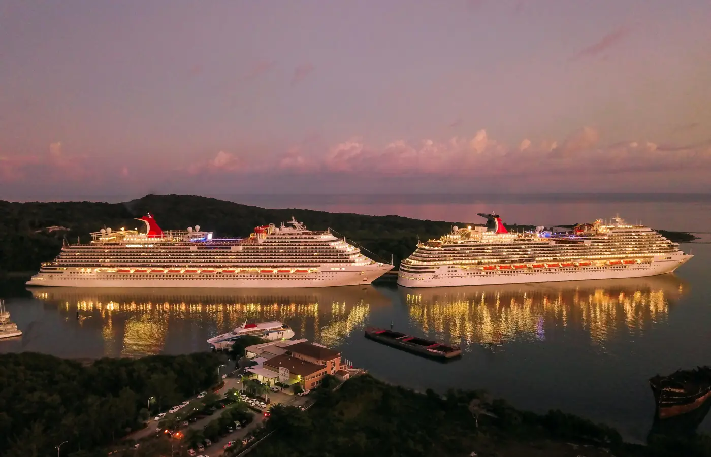 luxury cruise ships docked at sunset with lights reflecting on the water