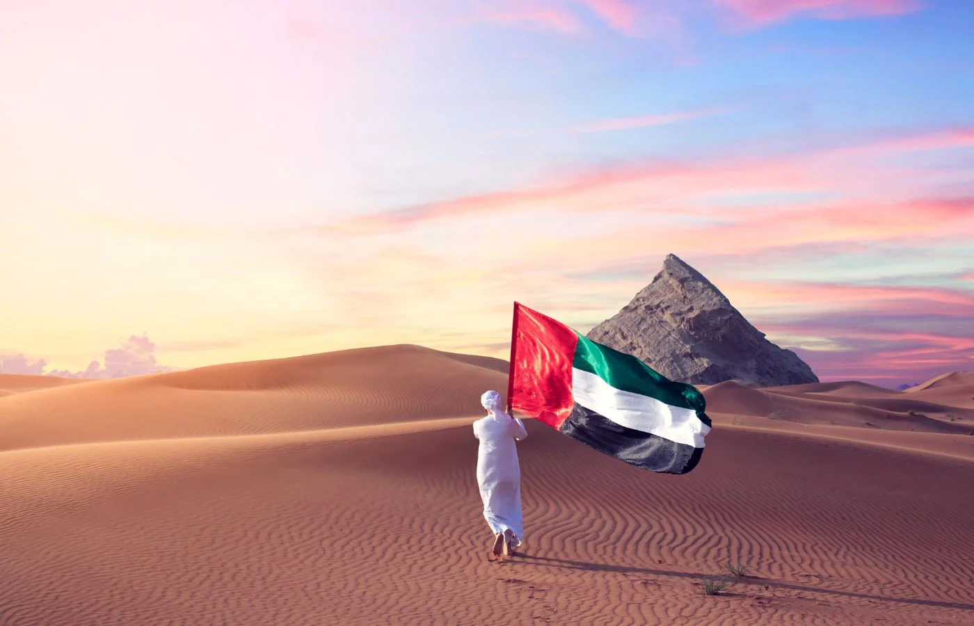 UAE National Day photo of a man waving the UAE flag in the desert
