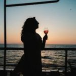 Woman holding a glass in hand while sailing in water.