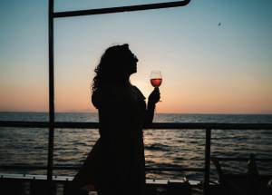 Woman holding a glass in hand while sailing in water.