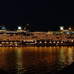 cruise ship cruises in water under night sky.