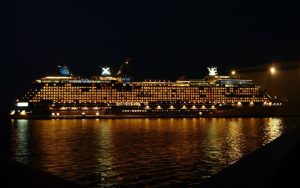 cruise ship cruises in water under night sky.