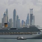 Cruise ship in city with skyscrapers in the body of water.