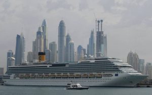 Cruise ship in city with skyscrapers in the body of water.