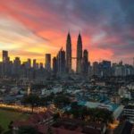 View of city buildings under orange sunset in Malaysia.