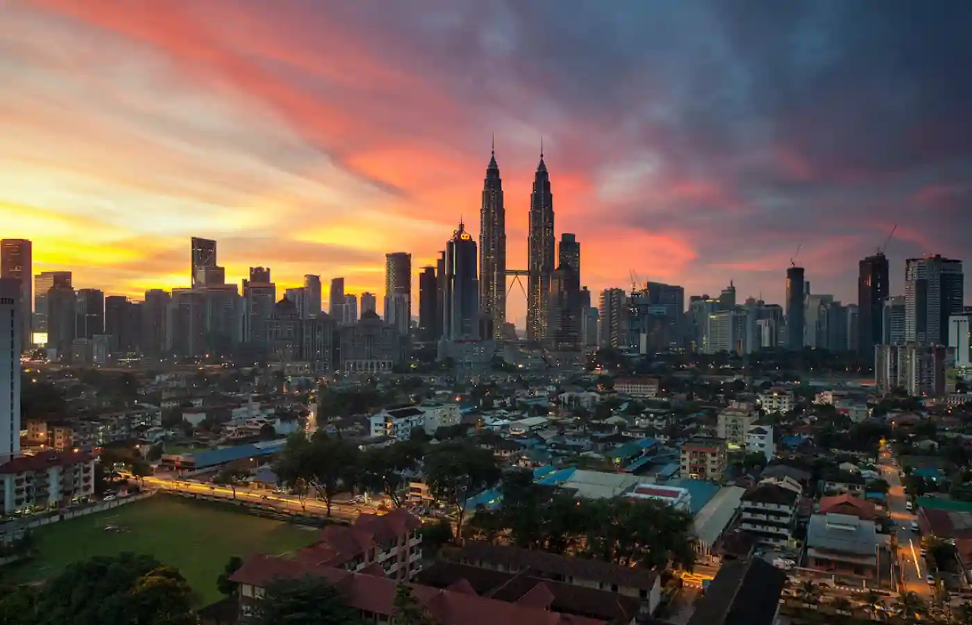 View of city buildings under orange sunset in Malaysia.