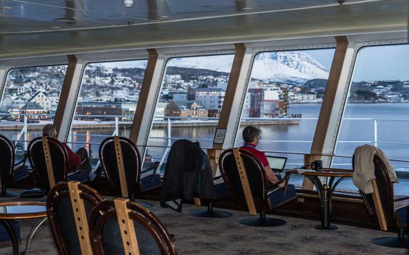 A man sitting in a cruise with laptop.