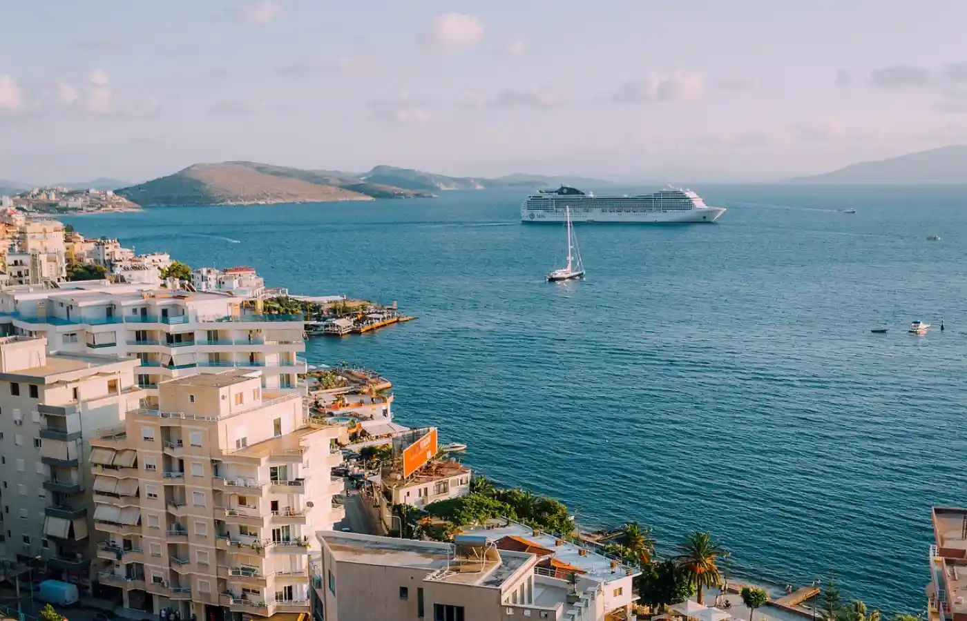 Buildings near the sea water with a cruise ship sailing in it.