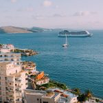 Buildings near the sea water with a cruise ship sailing in it.