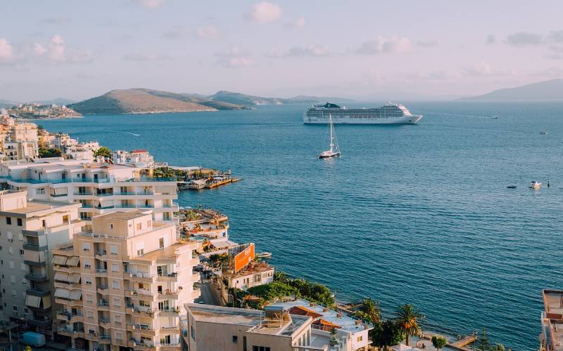 Buildings near the sea water with a cruise ship sailing in it.