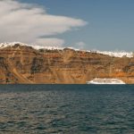 Mountains and hills by the sea under the sky with a cruise in water.