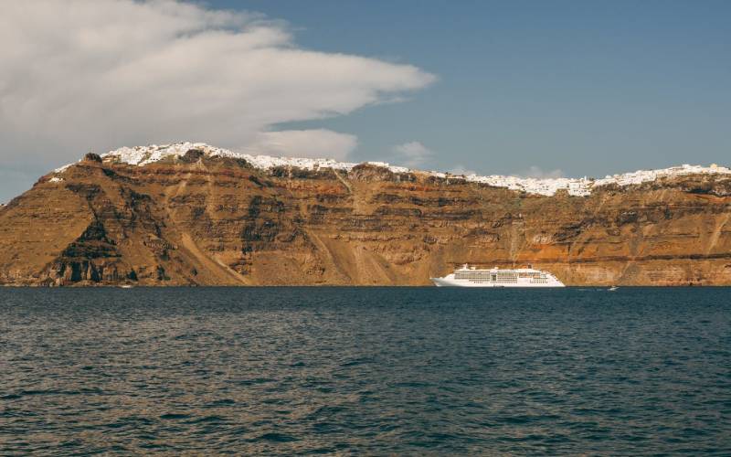 Mountains and hills by the sea under the sky with a cruise in water.