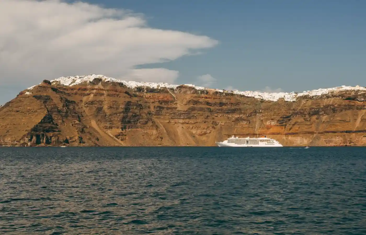 Mountains and hills by the sea under the sky with a cruise in water.