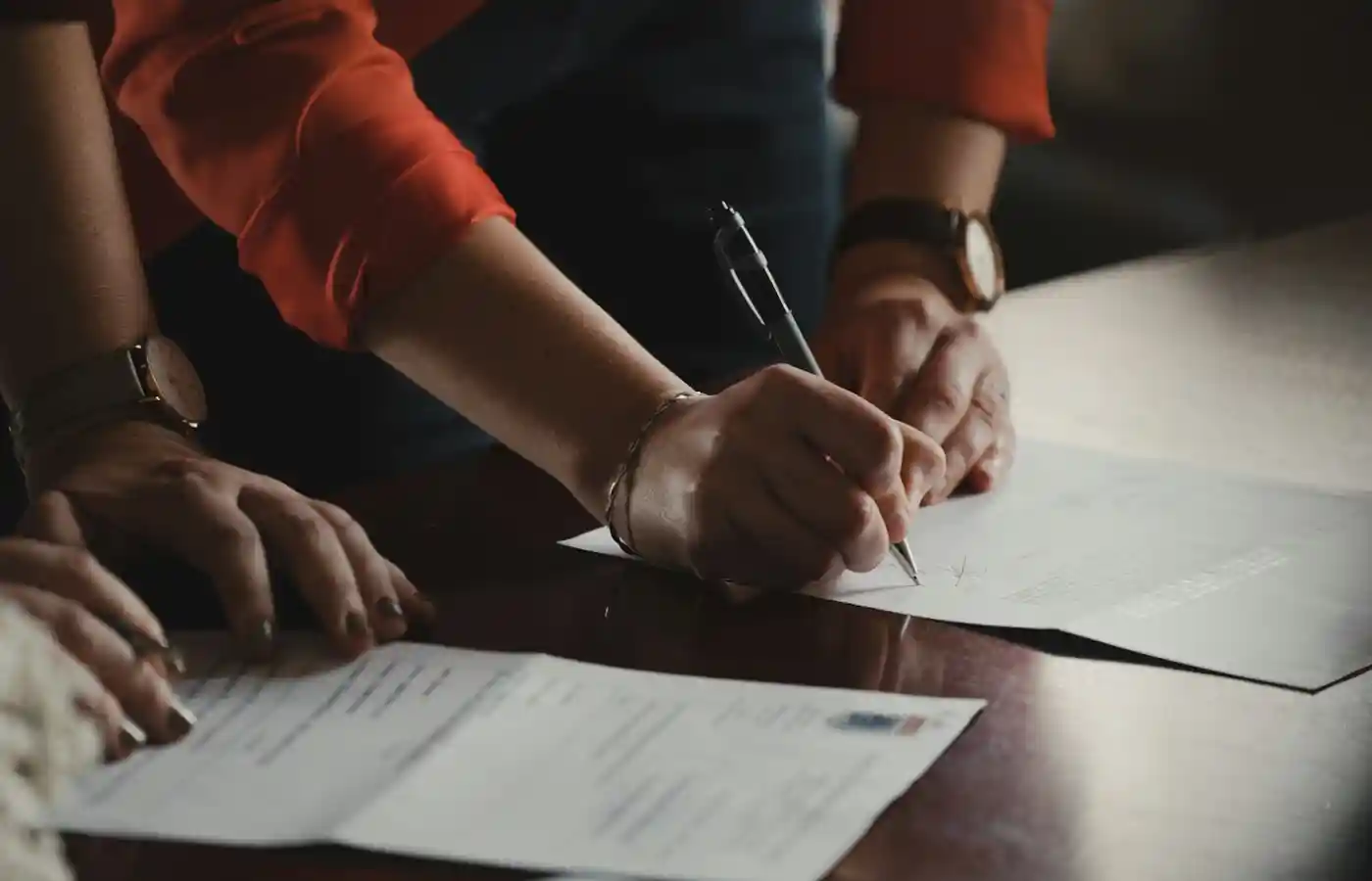 A man writing something on a white paper with pen.