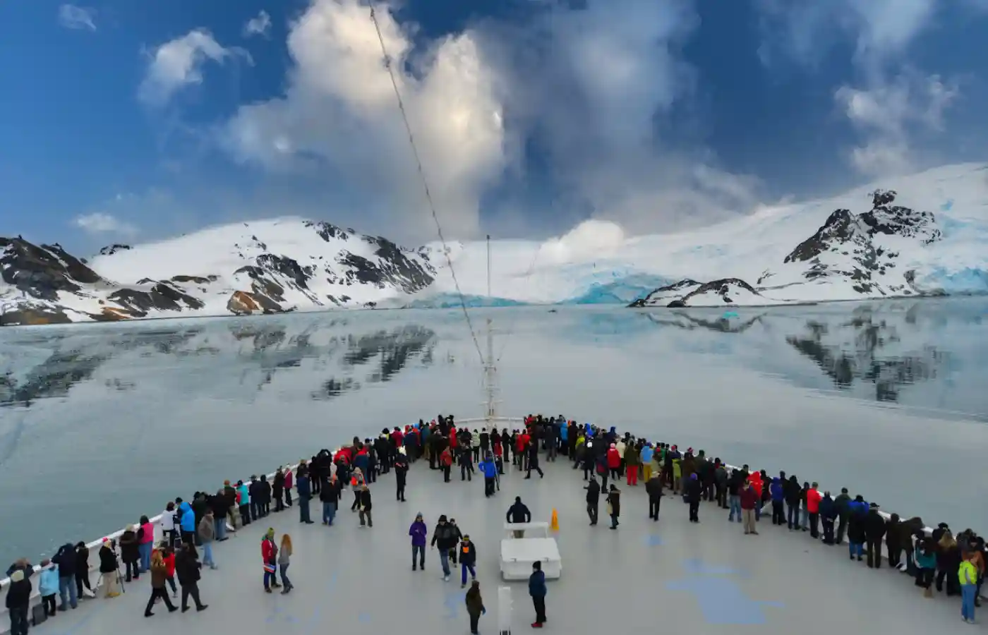 People aboard a cruise ship near snow covered mountain in Antartica.