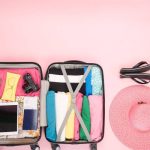 Pink color suitcase with travel essentials .