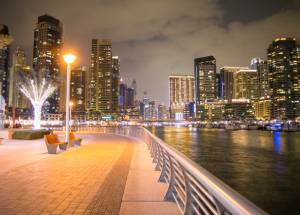 City buildings with lights near a body of water.