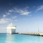 A white color cruise ship at a port.