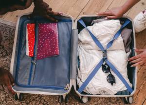 Clothes and Sunglasses in an Open Suitcase on a Rug