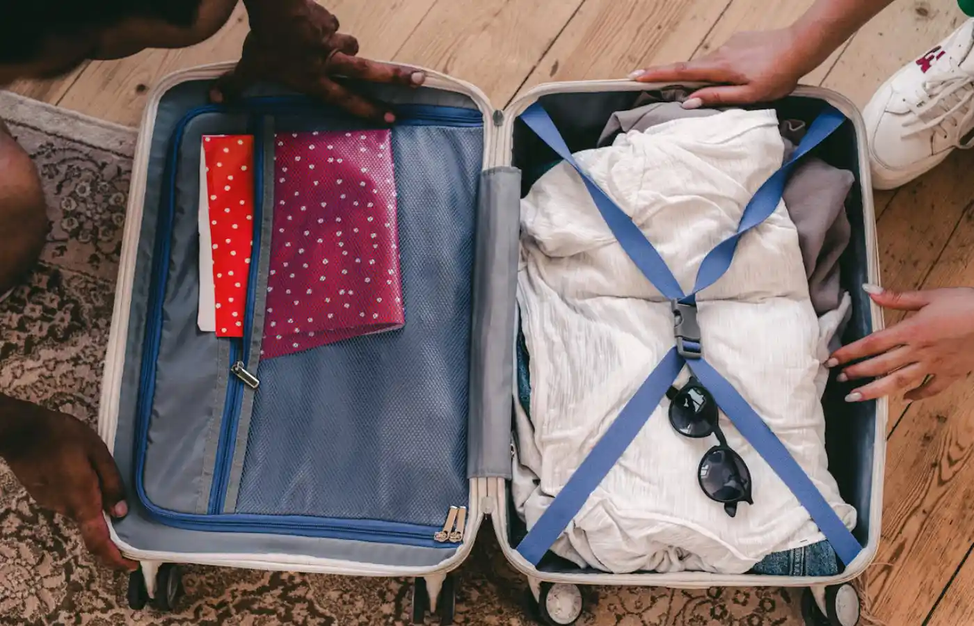 Clothes and Sunglasses in an Open Suitcase on a Rug