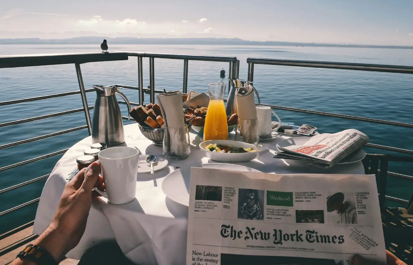 A person reading newspaper and having breakfast at a cruise.