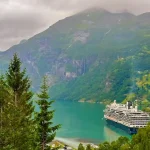 A cruise ship in the water surrounded by mountains.