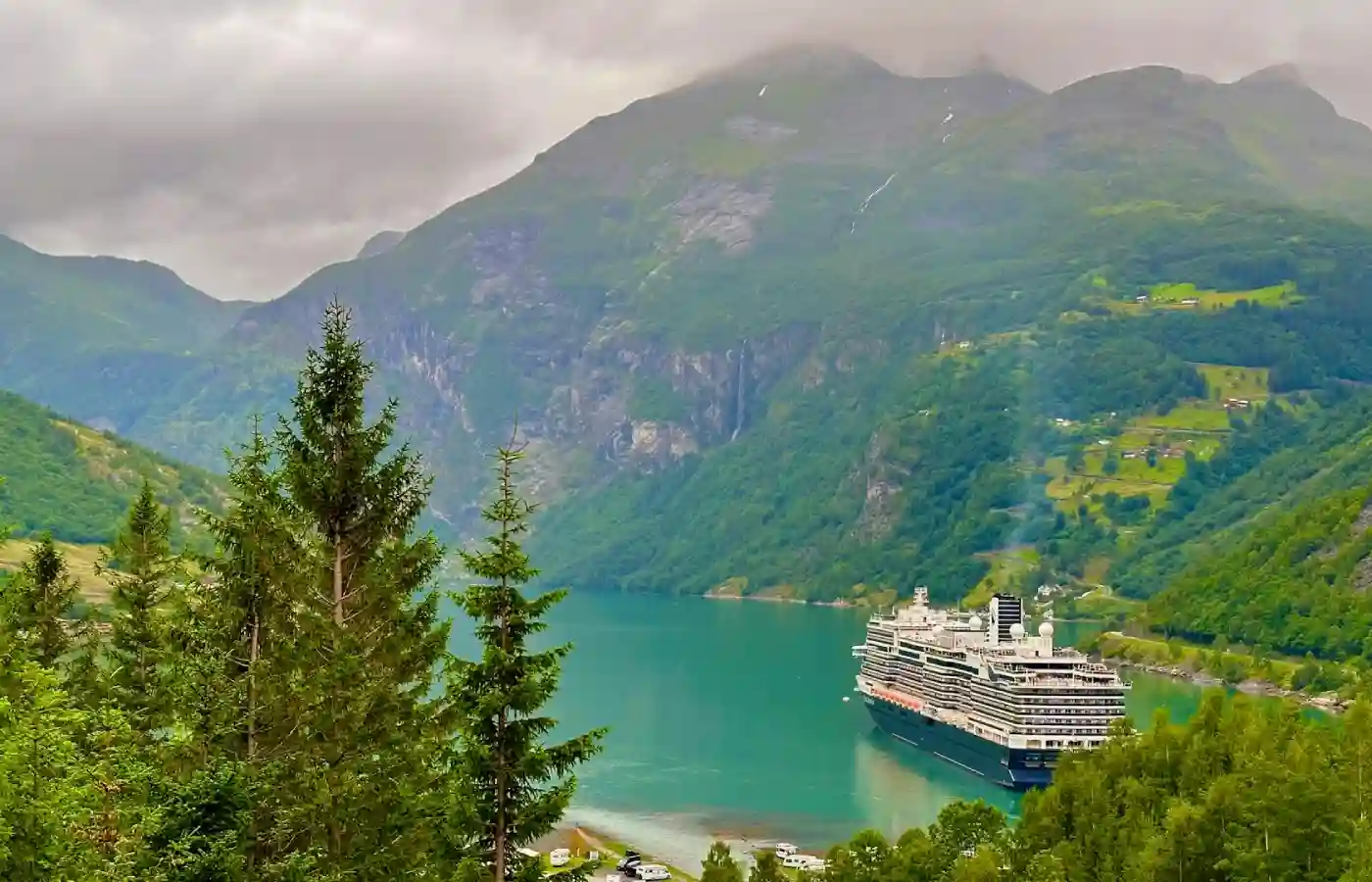 A cruise ship in the water surrounded by mountains.