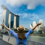 Young woman traveler with backpack and hat traveling into singapore city downtown.