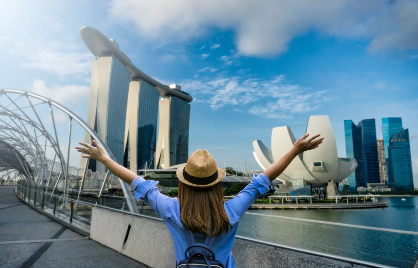 Young woman traveler with backpack and hat traveling into singapore city downtown.