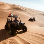 Man riding a dune buggy in desert.