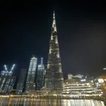 Tall building towering over a city at night in Dubai.