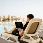 Man working on laptop at hotel pool