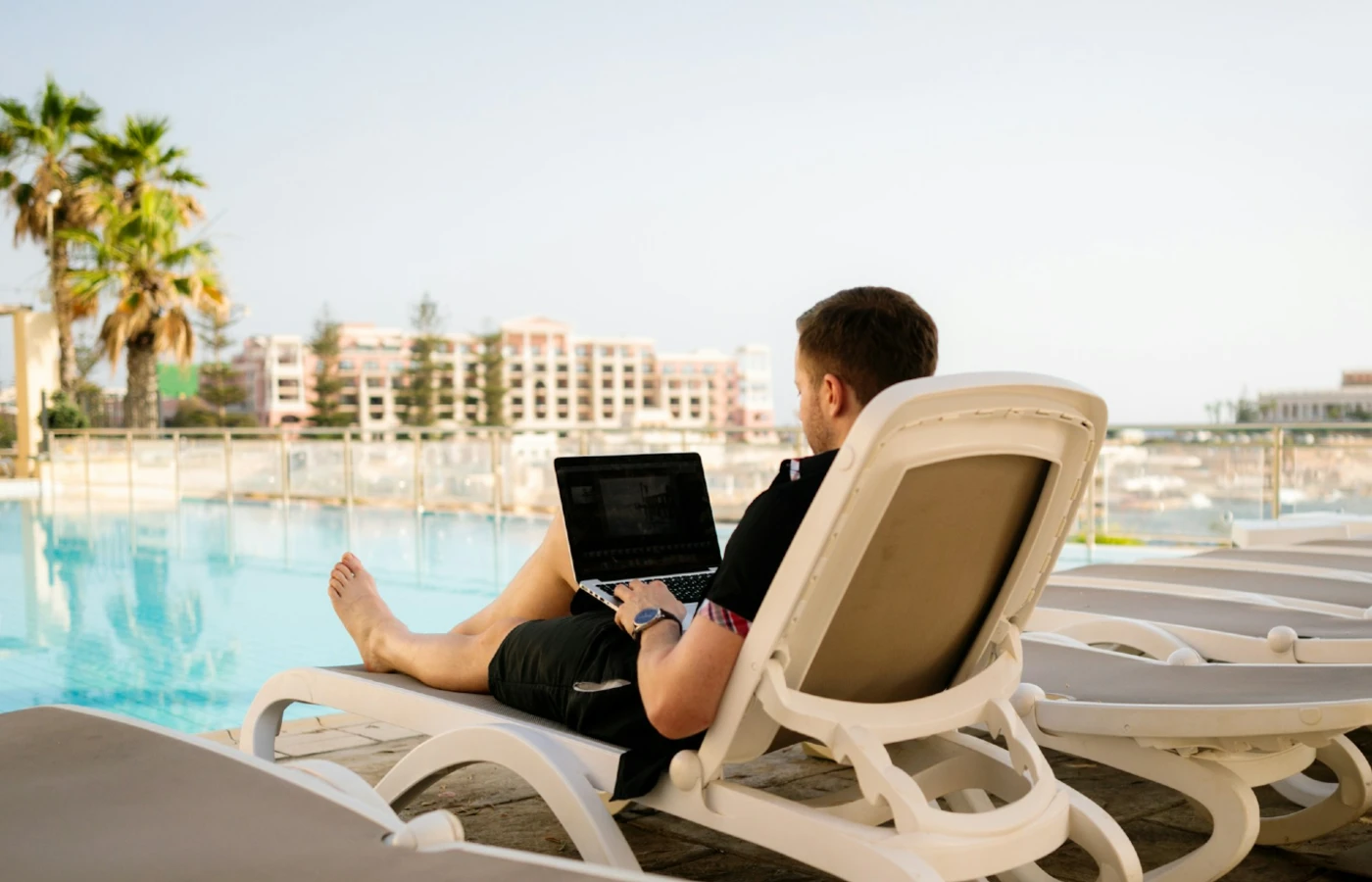 Man working on laptop at hotel pool