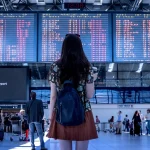 a woman watching the arrival and departure schedule at the airport terminal