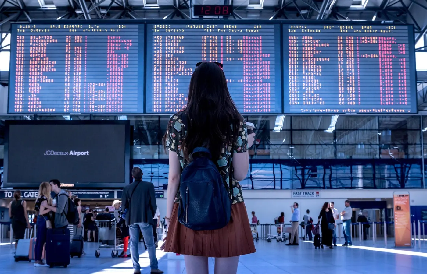 a woman watching the arrival and departure schedule at the airport terminal