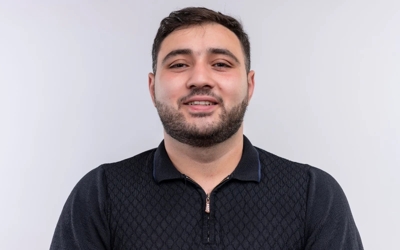 Young bearded man in black shirt looking at camera smiling happily