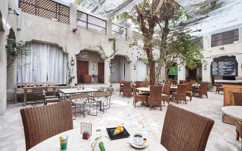 The interiors of XVA Art Hotel in Dubai with outdoor seating and a tree in the center