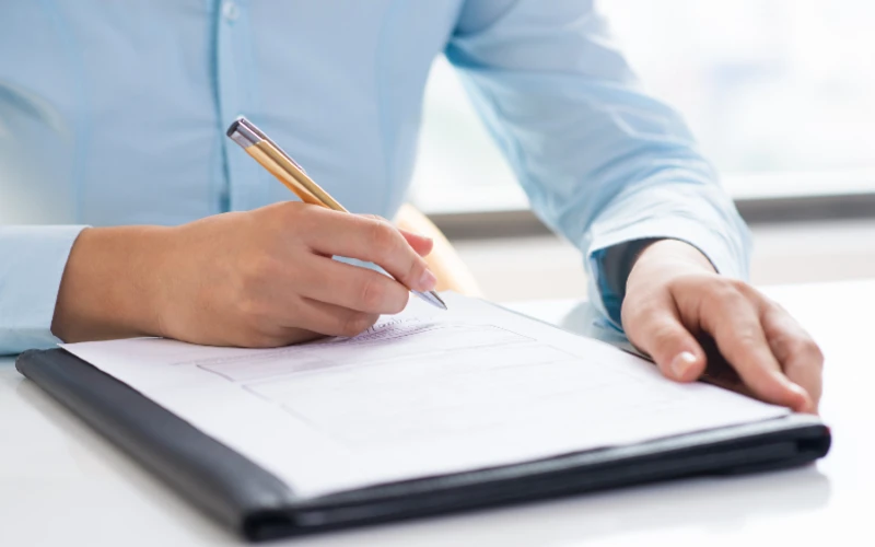 A person filling form by pen