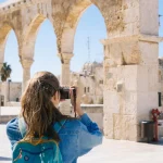 Woman photographing ancient ruins outdoors.