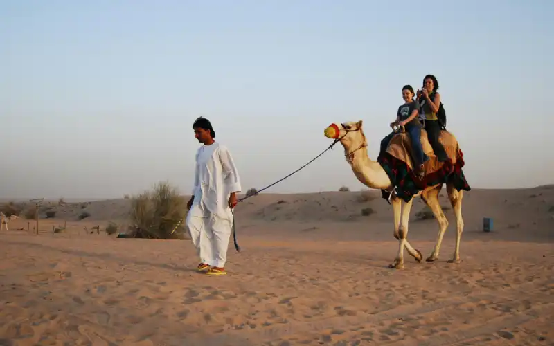 Woman with a girl riding on a camel in Dubai.